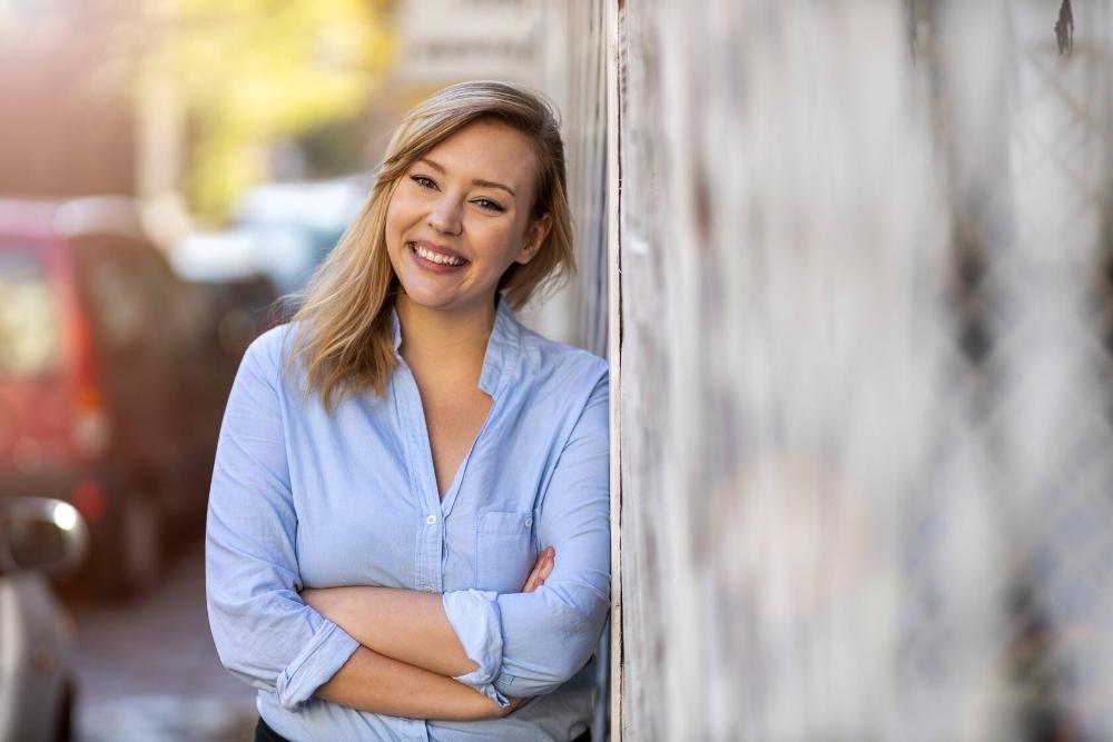 woman smiling while leaning against a building in northborough