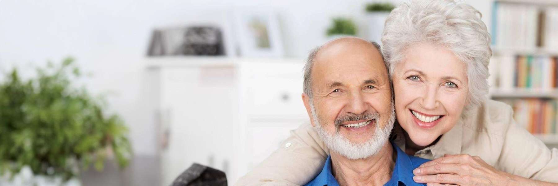 Smiling elderly couple embracing indoors.