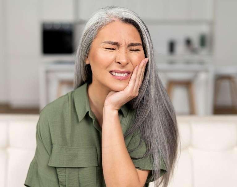 A woman holding her mouth in pain due to toothache in Northborough, MA