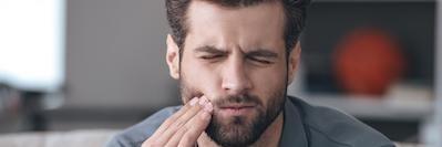man holding cheek from tooth pain before getting a root canal