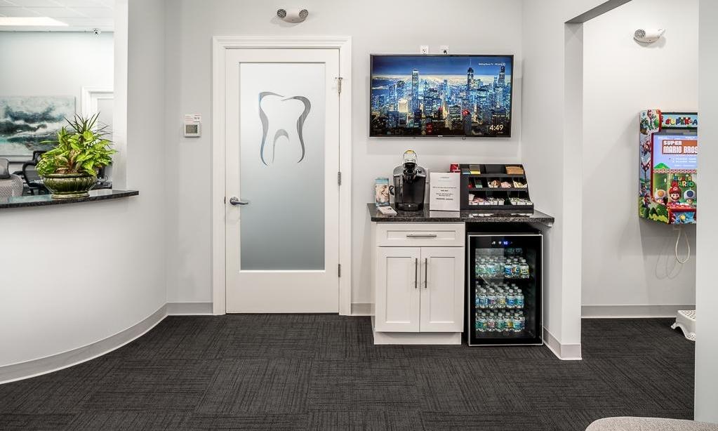 Coffee bar with coffee machine and water bottles in dental waiting room